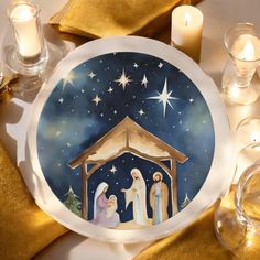 a plate with a nativity scene painted on it and lit candles in the background