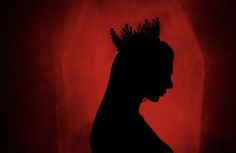 the silhouette of a woman with dreadlocks against a red background