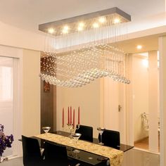 a chandelier hanging from the ceiling over a dining room table with black chairs