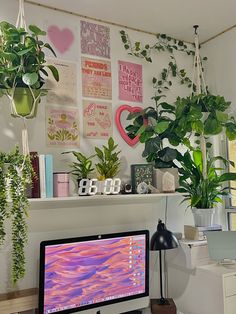 a desktop computer sitting on top of a desk next to a plant potted wall