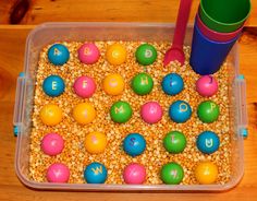 a plastic container filled with lots of different colored balls and letters on top of it