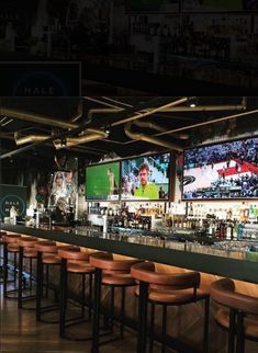 a bar with several televisions on the wall and wooden stools in front of it