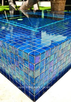 a blue tiled table sitting on top of a cement ground next to a palm tree