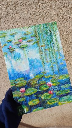 a person holding up a painting with water lilies on it