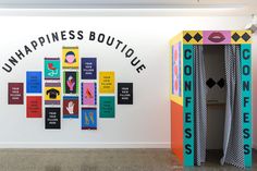 an art exhibit with colorful artwork on the wall and words that read, unhappiness boutique