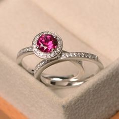 a close up of a ring in a box with a pink stone and diamond on it