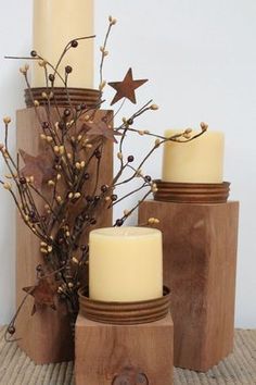 three candles are sitting next to each other on a wooden stand with branches and berries