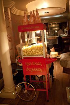 a popcorn machine sitting on top of a wooden floor next to a table with food