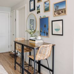 a table with two stools and pictures on the wall above it in a hallway