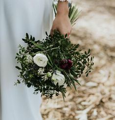 a woman holding a bouquet of flowers in her hand and wearing a white wedding dress