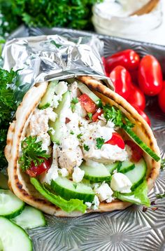 an open pita sandwich with cucumber, tomatoes and chicken