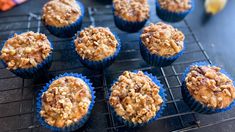 several muffins are cooling on a rack with blue paper liner cups next to them