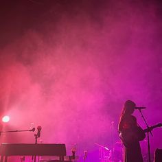 two people on stage with microphones and lights in the background, one person holding a guitar