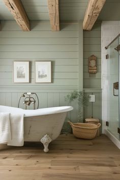 an old fashioned bathtub in a bathroom with wood flooring and green painted walls