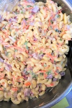 macaroni and cheese is mixed together in a large metal bowl on the stove