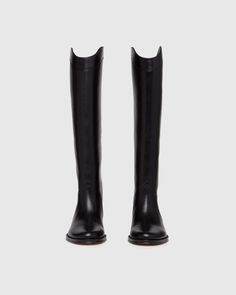 Raina is our take on the classic riding boot. Crafted from a super durable yet luxuriously soft black leather, this timeless straight shaft tall boot is designed with a curved topline that dips at the front and back for a flattering look, western-inspired pattern and stitch detailing, an extended leather welt with tonal stitch details, and a black leather stacked 20mm heel for a slight amount of lift. The classic menswear-inspired details on the outsole include stitching and half toplift for an Black Tall Boots Women, Black Boots Womens, Womens Tall Black Boots, Tall Western Boot, Capsule Wardrobe Women, Walking Tall, Classic Menswear, Womens Riding Boots, Fall Boots