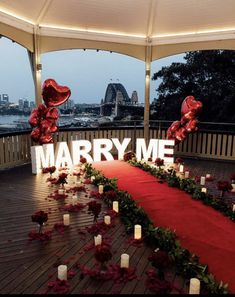 a red carpeted area with candles and flowers on it, surrounded by large letters that spell out marry me