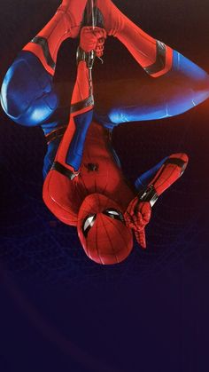 a spider man is hanging upside down in the air with his hands on his hips