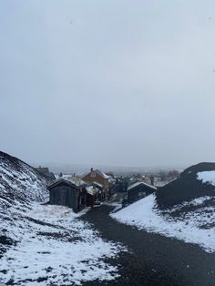 the road is covered in snow and there are buildings on both sides