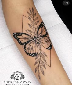 a black and white butterfly tattoo on the right arm, with leaves around it's wings