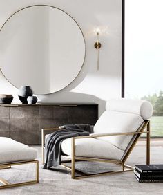 a living room with a chair, ottoman and round mirror on the wall above it