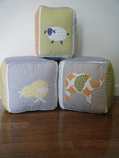 three pillows sitting on top of each other in the middle of a wooden floor next to a wall