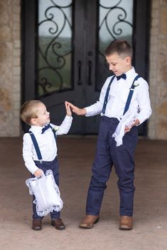 two young boys dressed in blue and white standing next to each other with their hands together