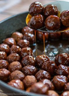 a spoon drizzling sauce over meatballs in a pan