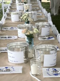 a long table is set up with buckets and place cards for guests to sign