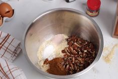 a metal bowl filled with dry ingredients on top of a white counter next to eggs