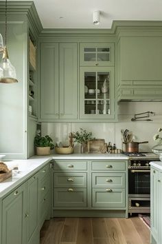 a kitchen filled with lots of green cabinets and white counter tops next to a stove top oven