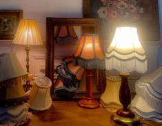 a table topped with lots of lamps next to a mirror and lamp shade on top of it