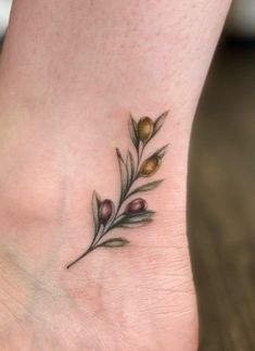 a small tattoo on the foot of a woman's foot with leaves and berries