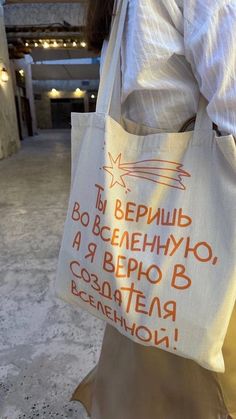 a woman carrying a white bag with orange writing on it