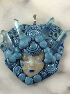 a blue and white pendant with an image of a woman's face in the center