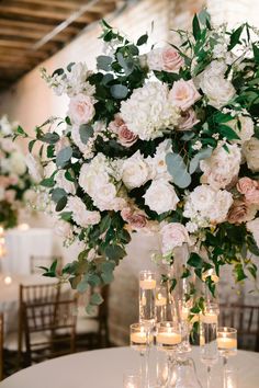 a vase filled with white and pink flowers on top of a table next to candles