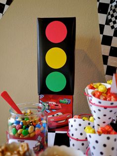 a table topped with lots of candy next to a traffic light and cupcakes