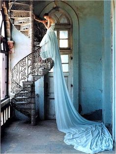 a woman in a white dress is standing on the stairs and looking down at something