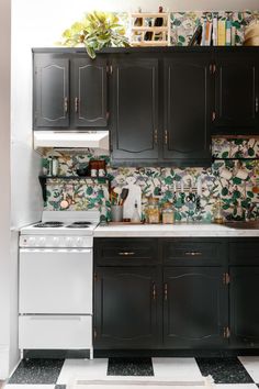 a kitchen with black cabinets and floral wallpaper on the backsplash is shown