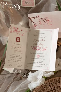 an open wedding card with flowers on it and the word love is written in pink