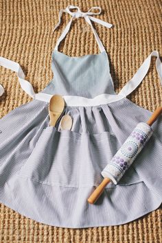 an apron and dress are laying on the floor next to some scissors, toothbrushes and other items