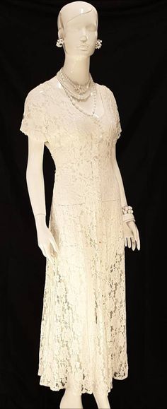 a mannequin wearing a white lace dress with pearls on it's neck