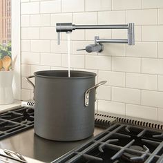 a pot is being filled with water from the faucet to the stove top