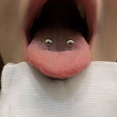 an open mouth with two piercings on it