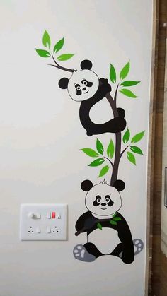 the pandas are hanging from the tree on the wall