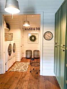 a wash and dry room with wood floors, green cabinets and a clock on the wall