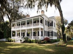 a large white house sitting on top of a lush green field