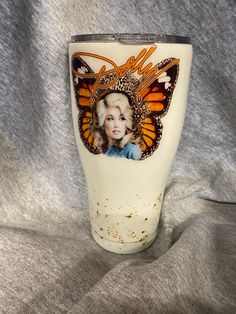 a white cup with an image of a woman on the side and orange butterflies around it