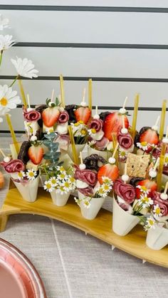 strawberries and chocolate covered strawberries are arranged in flower pots on a wooden platter