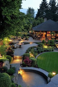 an outdoor patio with lights and landscaping in the evening time, surrounded by greenery